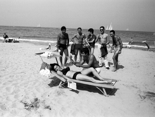Un gruppo di italiani corteggia l'hostess tedesca Nicole Steigleder in bikini su una sdraio. Un uomo le offre un mazzo di fiori. Riccione, agosto 1964
https://www.donnamoderna.com/benessere/psico/vacanze-anni-sessanta