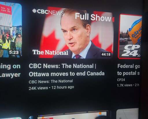 A photograph of the front page of YouTube, featuring a video titled "CBC News: The National | Ottawa moves to end Canada" posted by CBC News: The National. The thumbnail is a picture of [insert white male MBA/lawyer's name here], Minister of Labour. Fuck that guy. Fuckin' scab-ass motherfucker. Eat my shit and hair, [insert white male MBA/lawyer's name here]. Prick. Fuck you.