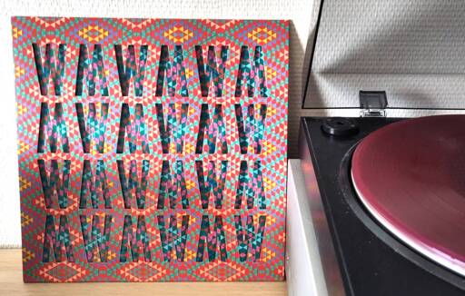 The "World music" LP cover has a geometric repeated mosaic pattern in bright colours. The outer sleeve is diecut with 24 alternating W/M shapes so you can see the inner cover's similar pattern in different colours. It's all pretty dizzying to look at.